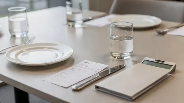 Restauranttisch mit Belegen und Taschenrechner zum Thema Bewirtungskosten absetzen