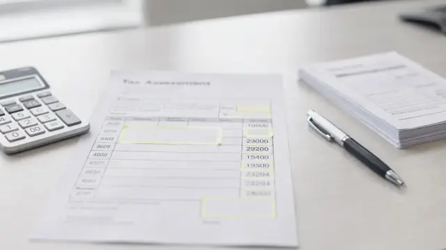 Steuerbescheid mit markierten Kennziffern neben Taschenrechner und Unterlagen auf einem Schreibtisch