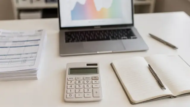 Steuerberater-Fehler: Unterlagen, Taschenrechner und Laptop auf einem Schreibtisch im Steuerbüro