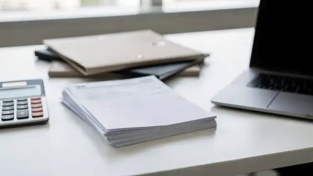 Steuerunterlagen mit Formularen, Taschenrechner und Ordner auf einem Schreibtisch zur Korrektur der Steuererklärung